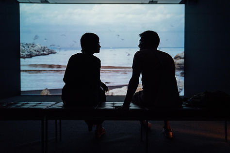 A couple sitting on a bench in front of the ocean talking about their relationship
