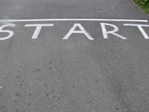 White START painted on asphalt with a starting line, suggesting a race or route beginning; greenery borders the path above.