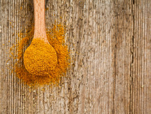 Ground turmeric on a wooden spoon, the spice that curcumin is extracted from