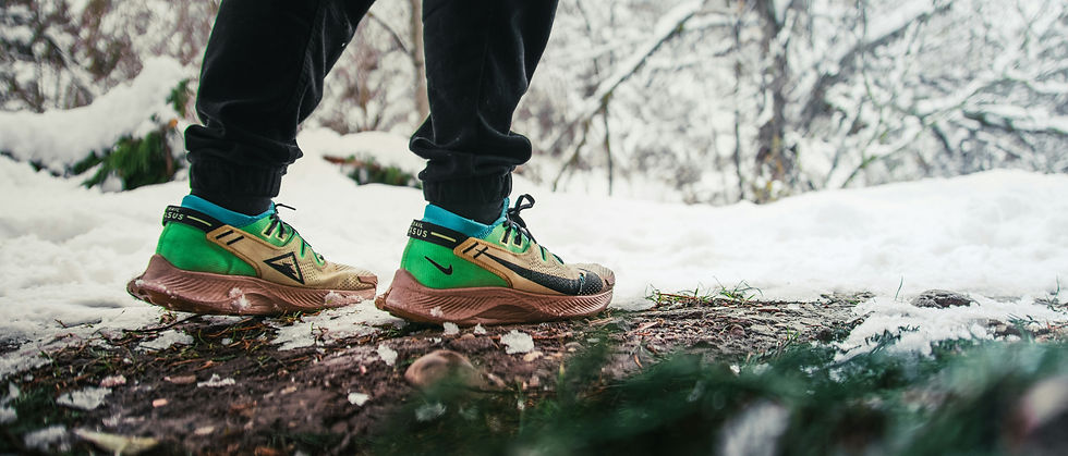 Low shot of running shoes on a forest floor surrounded by snow