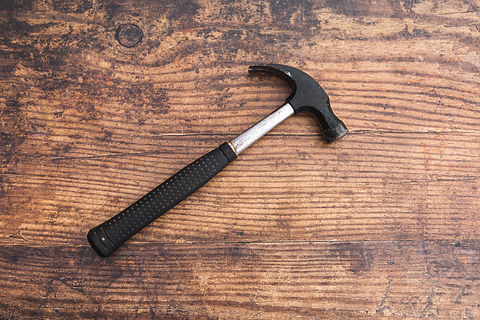 Image shows a hammer on a wooden floor.