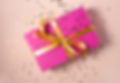 A gift wrapped in pink paper, with a gold ribbon.