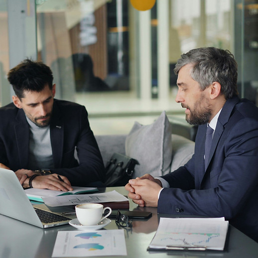 Three professionals reviewing documents and a laptop during an office meeting