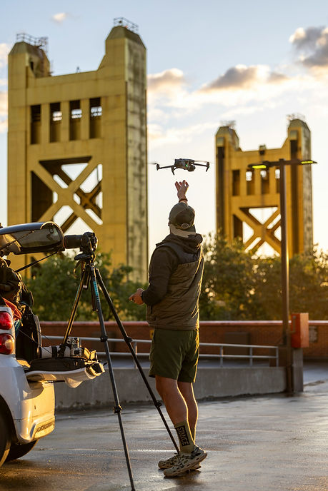 Operator launching a drone near a bridge during event filming