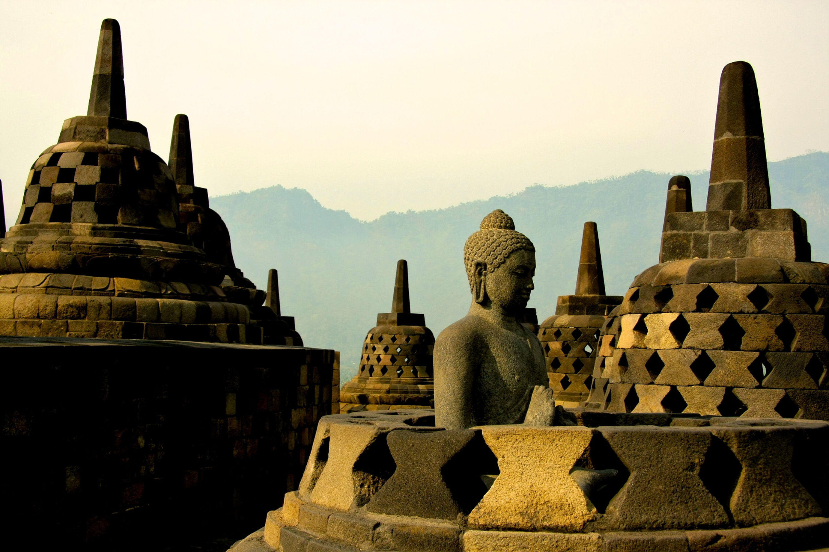 Buddha statue among stone stupas at Borobudur Temple