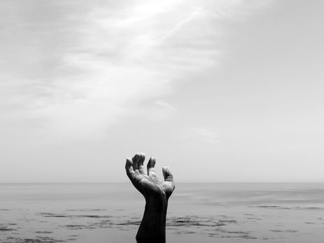 Black and white image of hands reaching upward from water, symbolizing emotional buildup, awareness, and release
