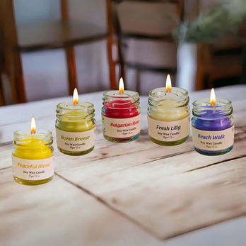Five lit scented candles in jars on a wooden table