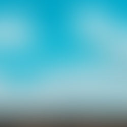 Fluffy white clouds float in a vibrant blue sky above a dense, dark green forest. The scene conveys a calm and serene mood.