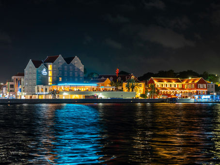 Willemstad Curaçao waterfront at night, the colorful Handelskade facades lit over the water