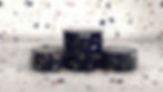 Three black cylinders with terrazzo pattern stand on a speckled surface. The background mirrors this pattern, creating a cohesive look.