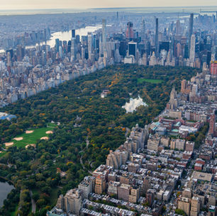 Aerial view of Central Park and the Manhattan skyline on a clear day, showcasing the Upper East Side, Midtown skyscrapers, tree-lined park landscapes, and surrounding New York City architecture from above.