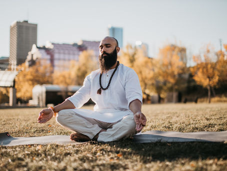 Man in meditation on the grass outside the city. Photo by Redd Francisco