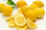 Fresh whole lemons and sliced lemons.