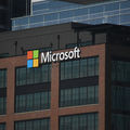 Microsoft logo on a brick building with large windows. The colorful logo stands out against the corporate, modern facade.