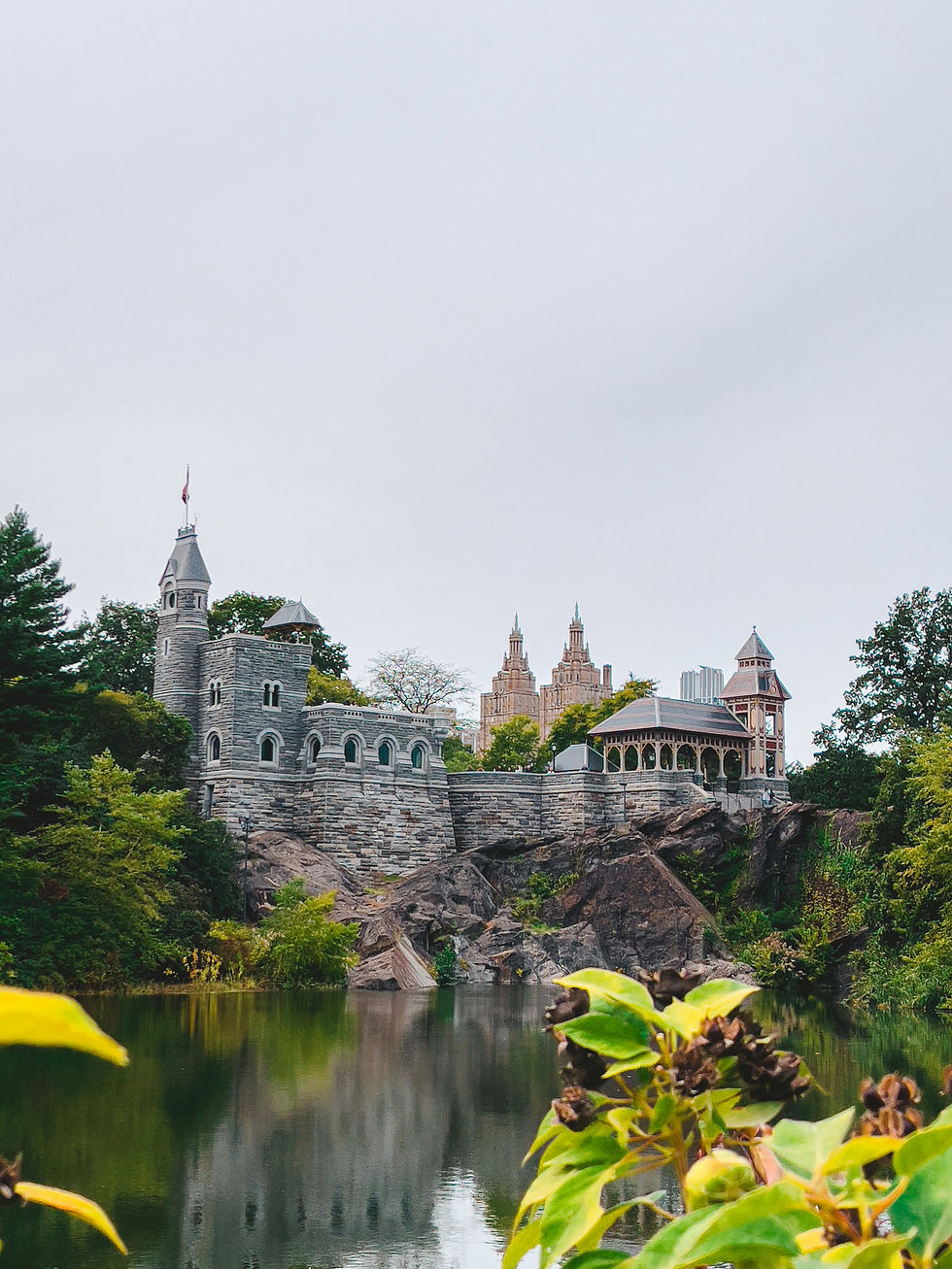 A picturesque view of Belvedere Castle in Central Park, New York City, surrounded by lush greenery and reflected in the tranquil waters below.