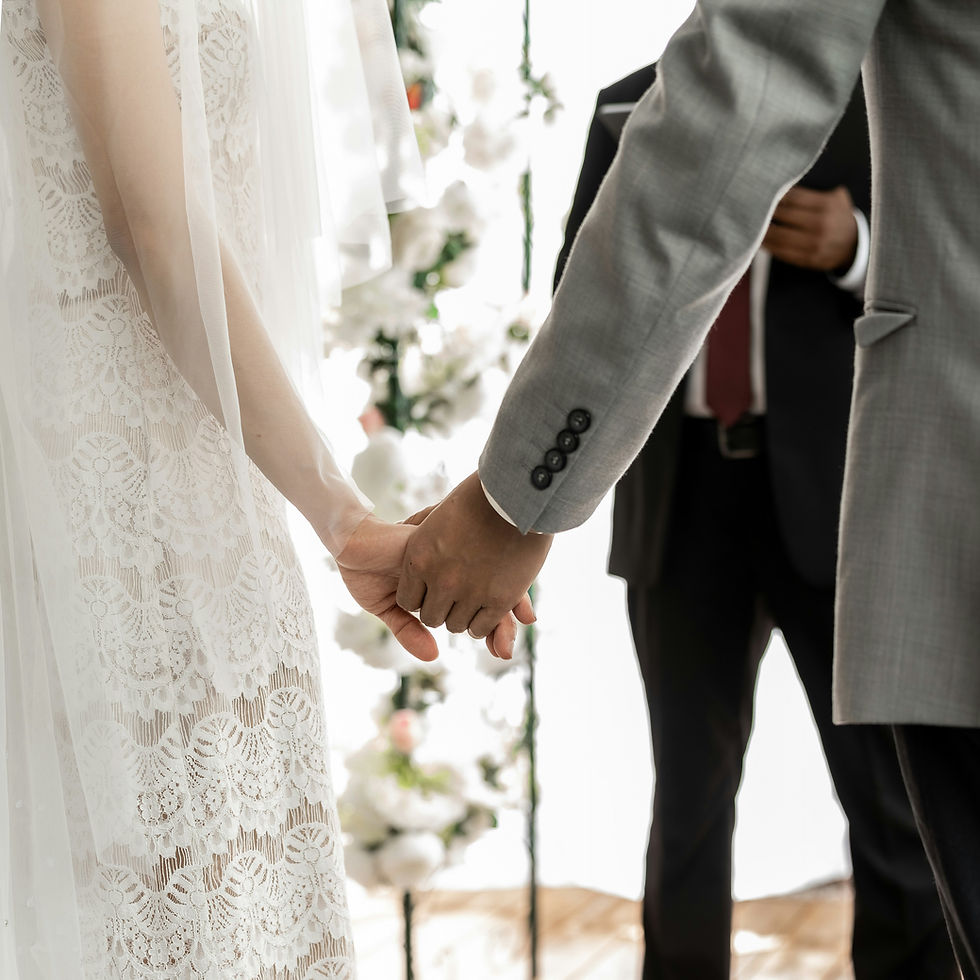 Les mariés se tiennent la main lors d'une cérémonie de mariage en plein air, sous une arche fleurie et avec des chaises.