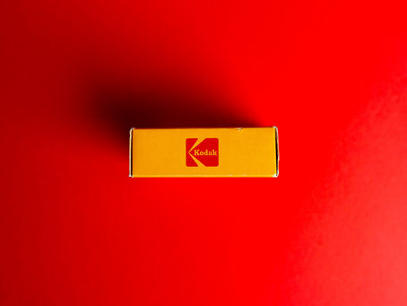 Yellow Kodak box centered on a red background, displaying the Kodak logo in red. Minimalistic and vibrant composition.