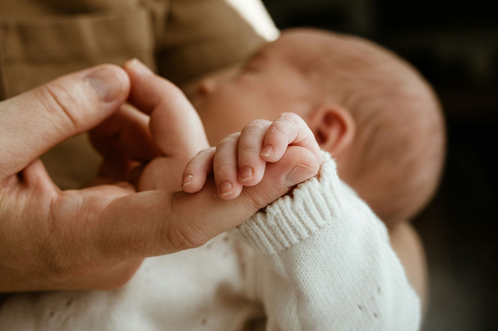 A parent holding their baby's hand