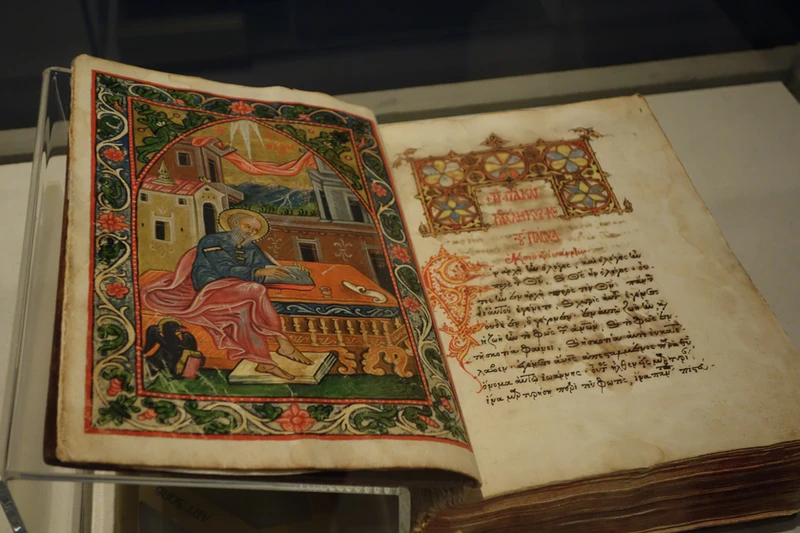 An open illuminated medieval codex with hand-painted illustrations, representing the earliest Christian writings after the New Testament