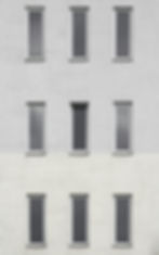 Gray building facade with nine uniform, vertical windows in three rows. The surface texture is rough, creating a minimalist and serene mood.