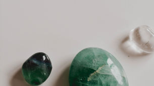 colourful stones, one dark green, one lighter green and one transparent lying together on a white background