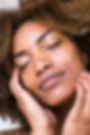 Close up African American woman, glowing skin, hands resting on cheeks, eyes closed, relaxed look, closed mouth smile