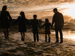 A family walking on a beach at sunset.