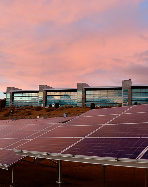 Building in the background and solar panels ground mounted in the foreground