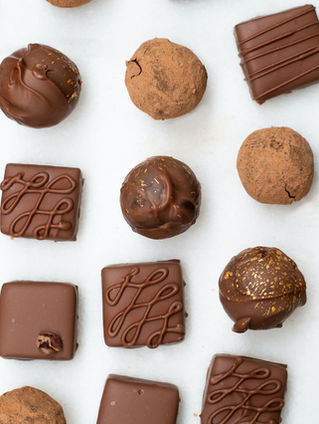 Handcrafted artisan chocolates and truffles from chocolate brands in Bali, arranged on a white background with assorted pralines and cocoa-dusted treats.