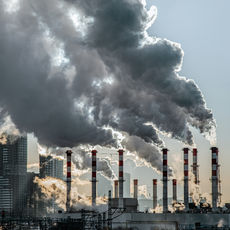 Seven smokestacks send plumes of smoke high into the sky.