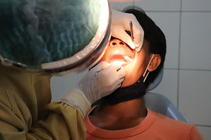 a dentist peering into a male patient mouth for a surgical procedure