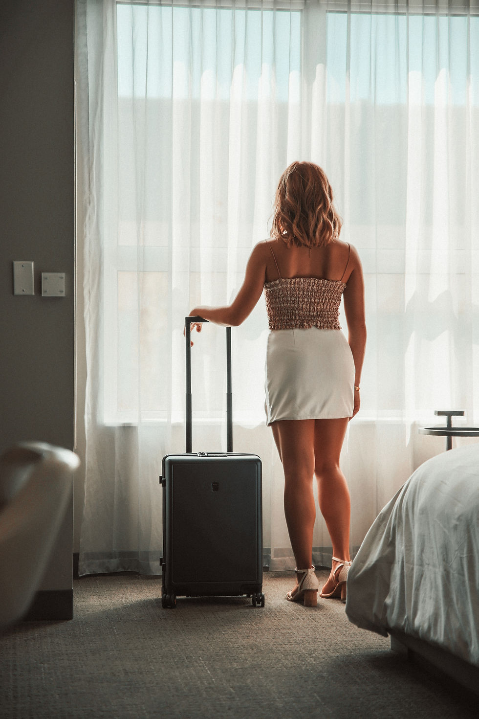Une femme qui tient une valise dans une chambre d'hôtel