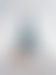 Yogini in blauem Outfit übt das ganze Rad mit gestreckten Bein nach oben. Sie befindet sich zwischen weissen Arkaden