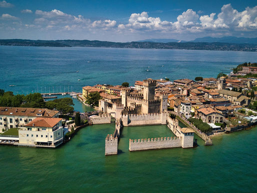 Veduta aerea di Sirmione con le mura del Castello Scaligero che si affacciano sul Lago di Garda, in un luminoso Weekend d’estate a Sirmione.