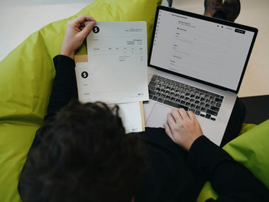 Een man die een factuur bekijkt naast zijn laptop.