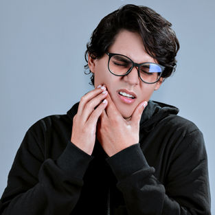 boy holding his cheek as a sign of jaw pain