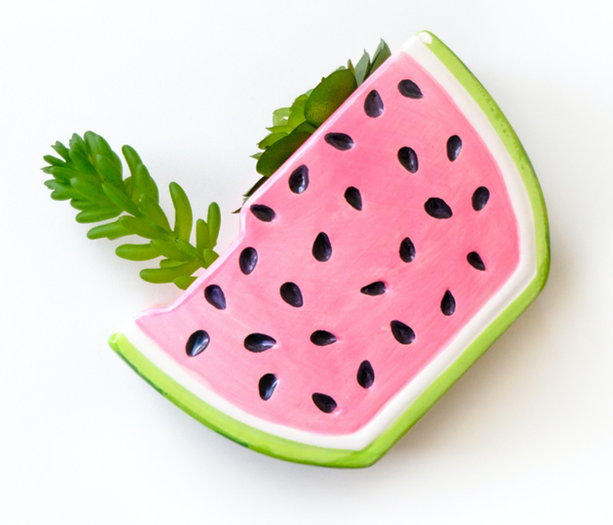 Pink watermelon-slice brooch with black seeds and green rind, isolated on a white background