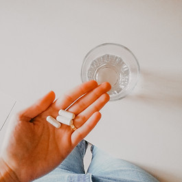 A hand holding several white pills or capsules, with a light-colored background.Image by Mariana Rascão