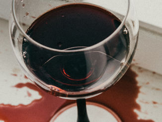 Red wine spill beside a wine glass before professional stain treatment