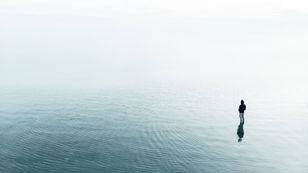 Person standing alone in calm water