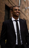 A man in a suit smiling while walking down the street after a life coaching session