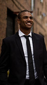 A man in a suit smiling while walking down the street after a life coaching session