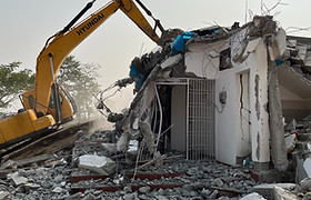 Excavator carrying out controlled building demolition