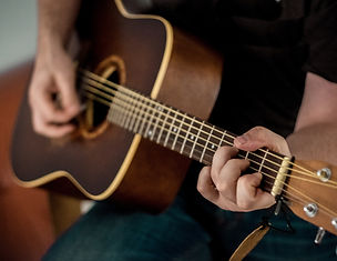 A man holding an acoustin guitar for live music held at Bremer Brewing Company in Waverly, Iowa.
