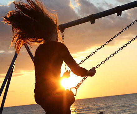 Woman on swing at sunset