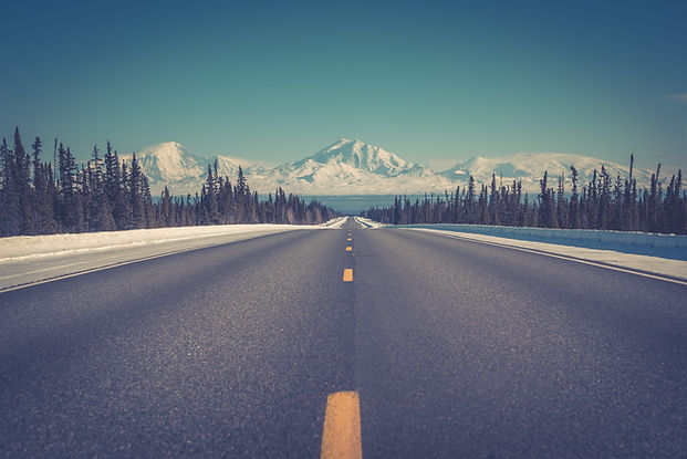 a street level view of a highway with center line leading to a horizon of mountains. Image by Bryan Goff