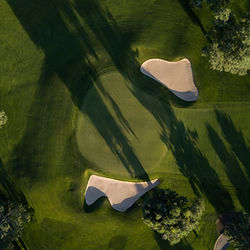 Un golfeur talentueux réalise un putt parfait sur un green impeccablement entretenu, sous le regard attentif de ses amis.