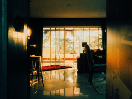 Alt text: An empty living room at sunset with warm light fading through the windows, symbolizing the emotional distance, silence, and withdrawal that can happen in relationships when conflict feels unsafe or overwhelming.