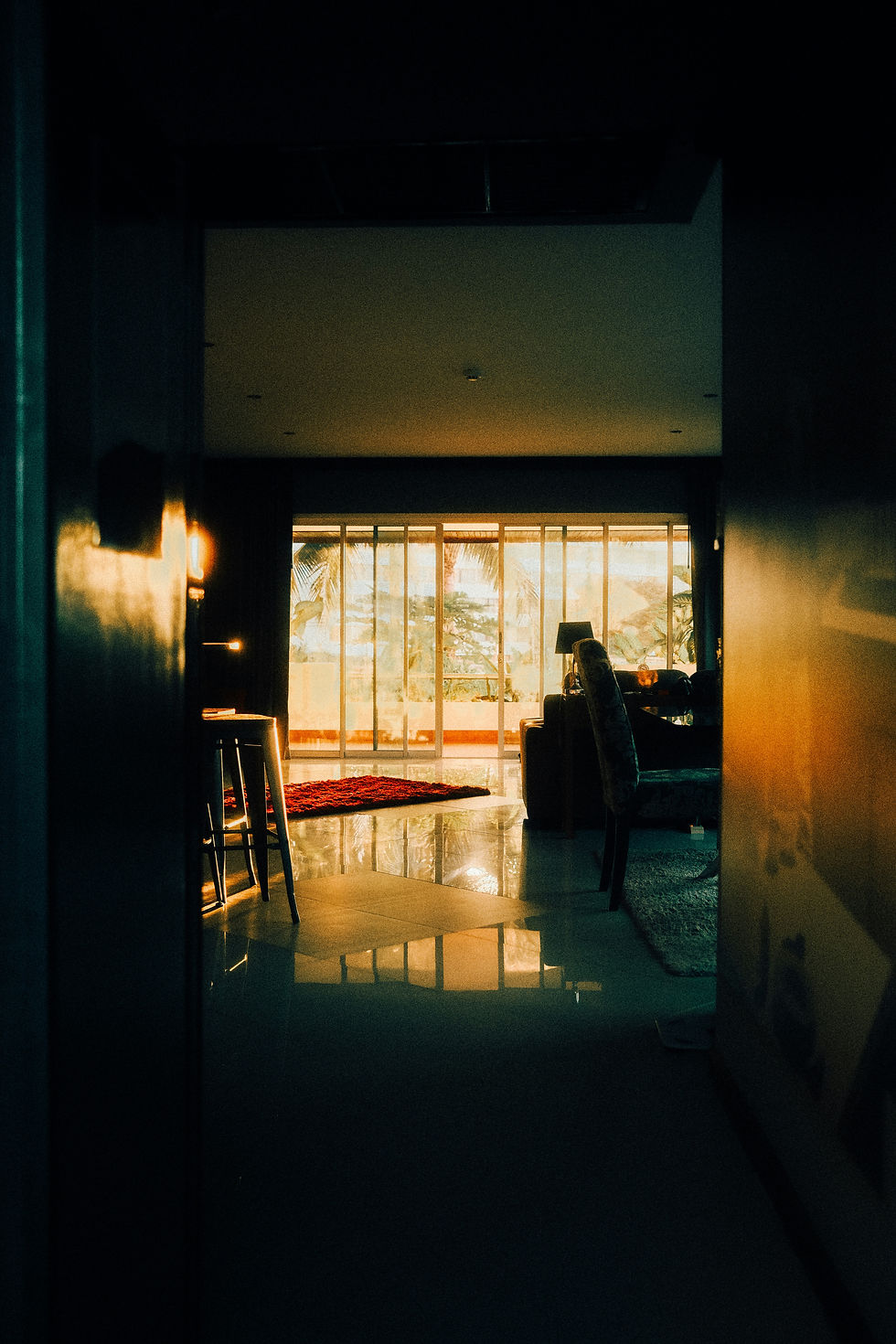 Alt text: An empty living room at sunset with warm light fading through the windows, symbolizing the emotional distance, silence, and withdrawal that can happen in relationships when conflict feels unsafe or overwhelming.