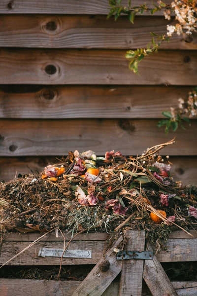 a pile of compost sits in front of a wooden fence
